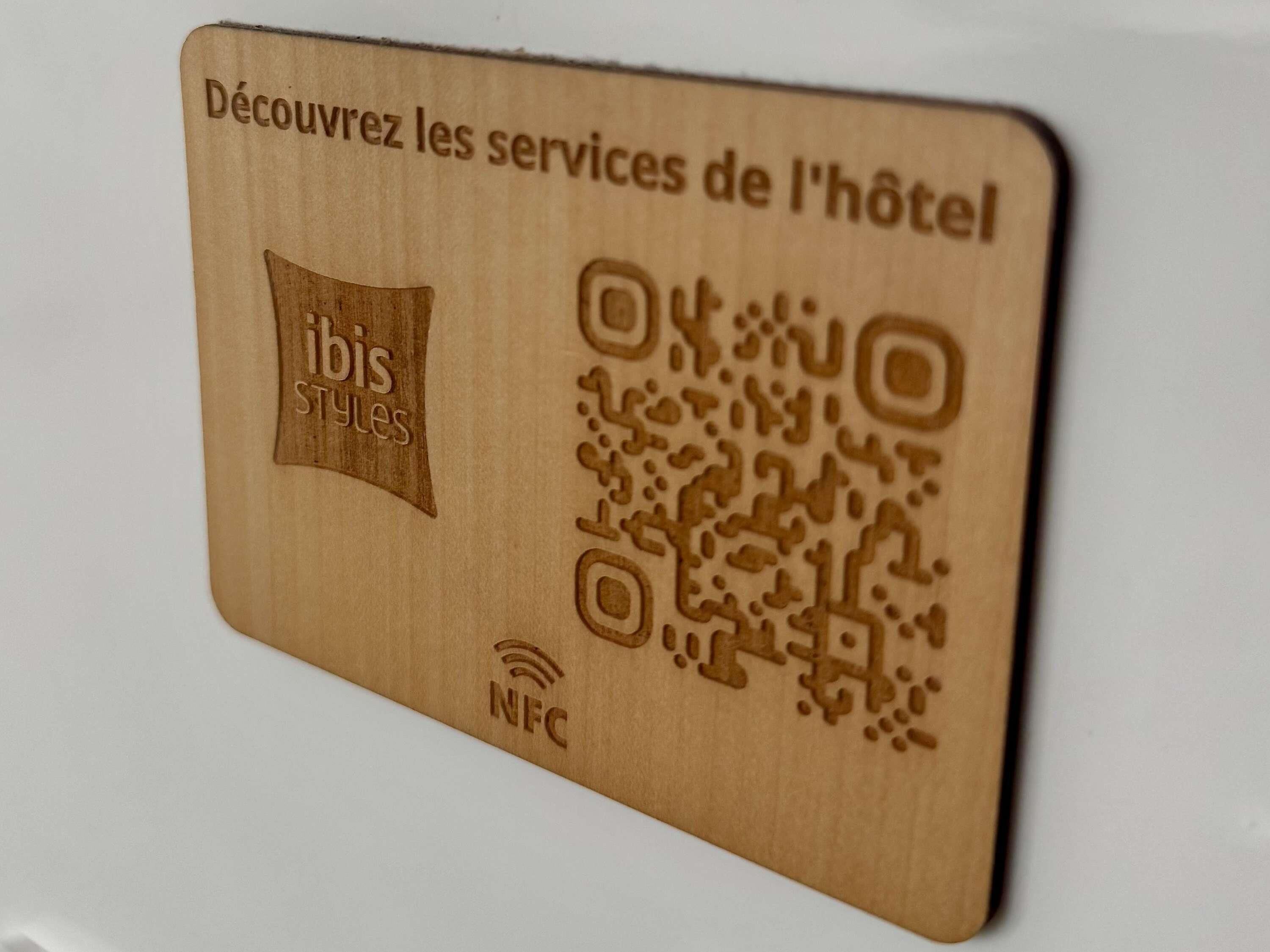 A wooden hotel service card with a QR code and NFC symbol.