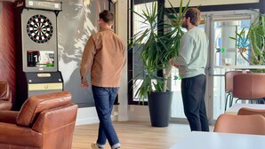 A modern lounge area with leather furniture, a dartboard, and a potted plant. - ibis Styles Bordeaux Saint Médard (Saint-Medard-en-Jalles)