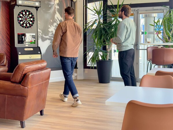 Een moderne lounge met lederen meubels, een dartbord en een potplant.