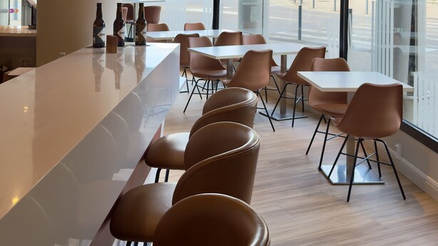 A modern bar area with a long counter, seating, and large windows. - ibis Styles Bordeaux Saint Médard (Saint-Medard-en-Jalles)