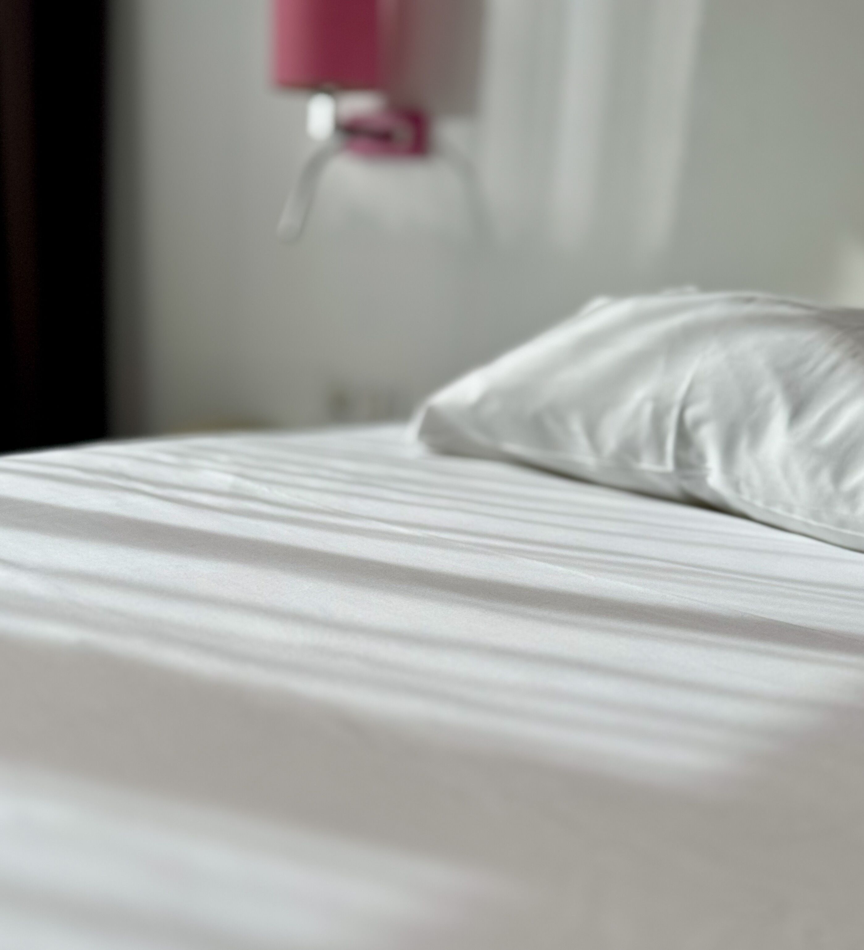 A bed with white bedding and a pillow.