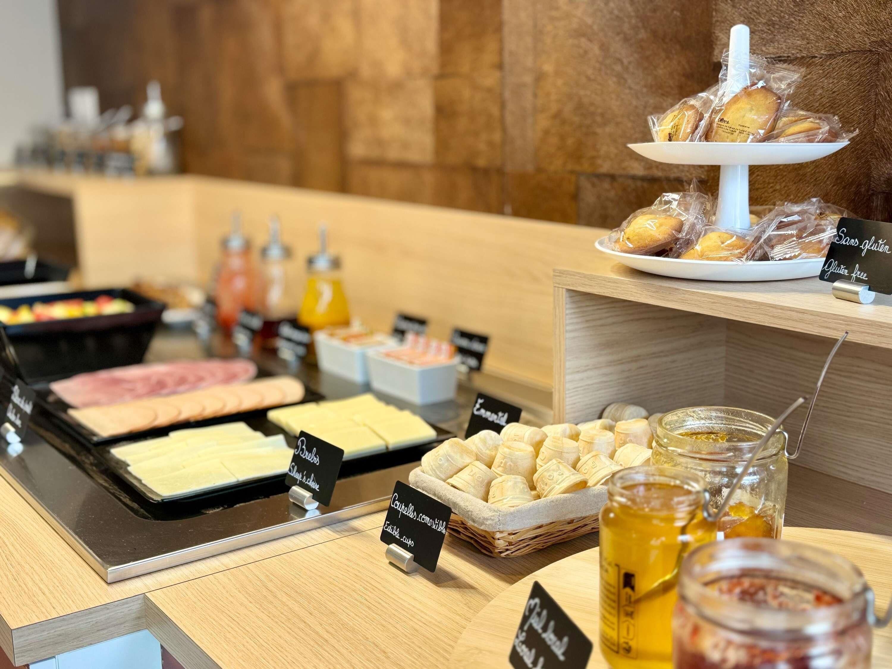 A buffet with various food items, including meats, cheeses, and bread, with labels indicating dietary options.
