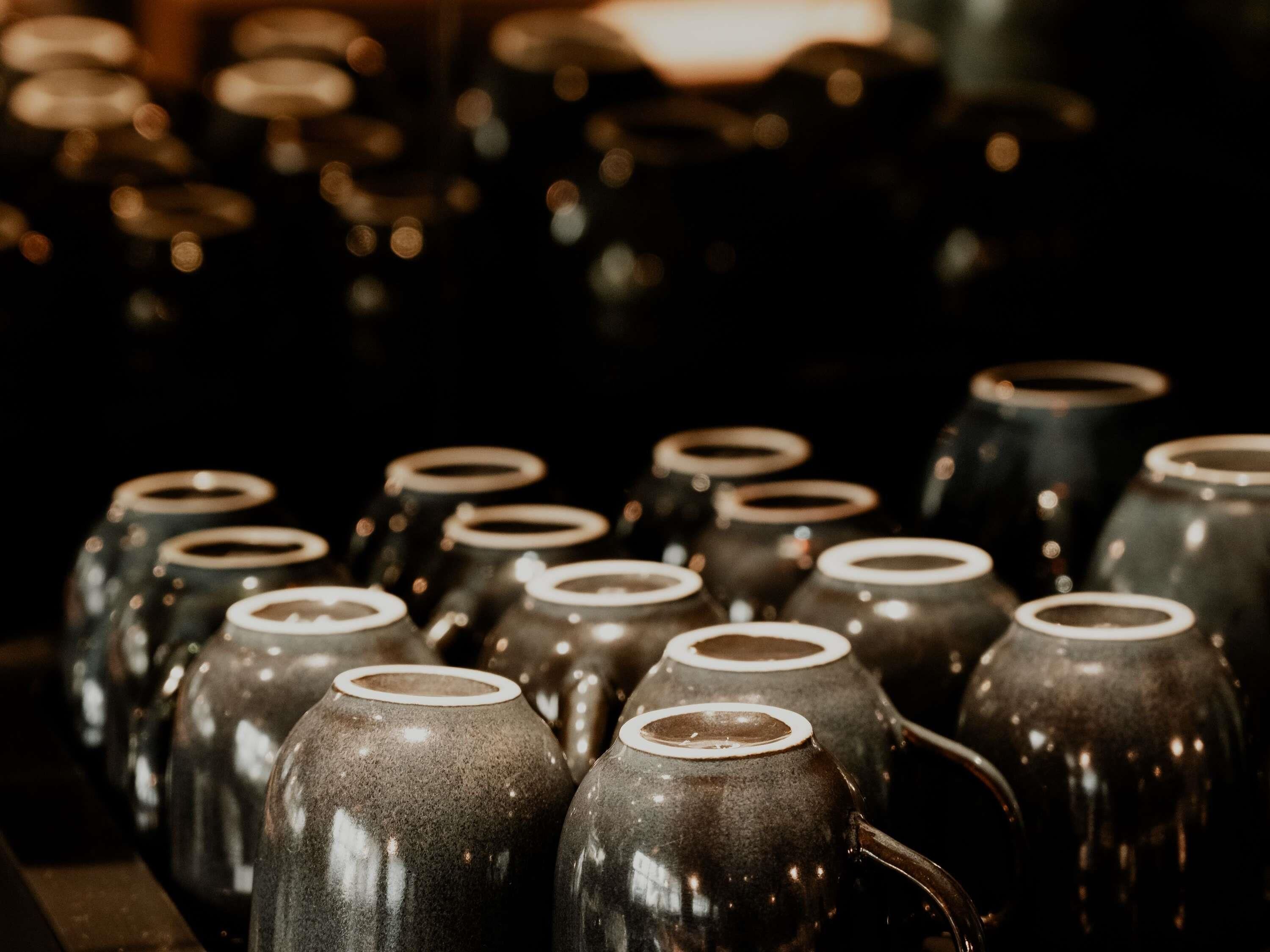 A collection of ceramic mugs with handles, arranged closely together.