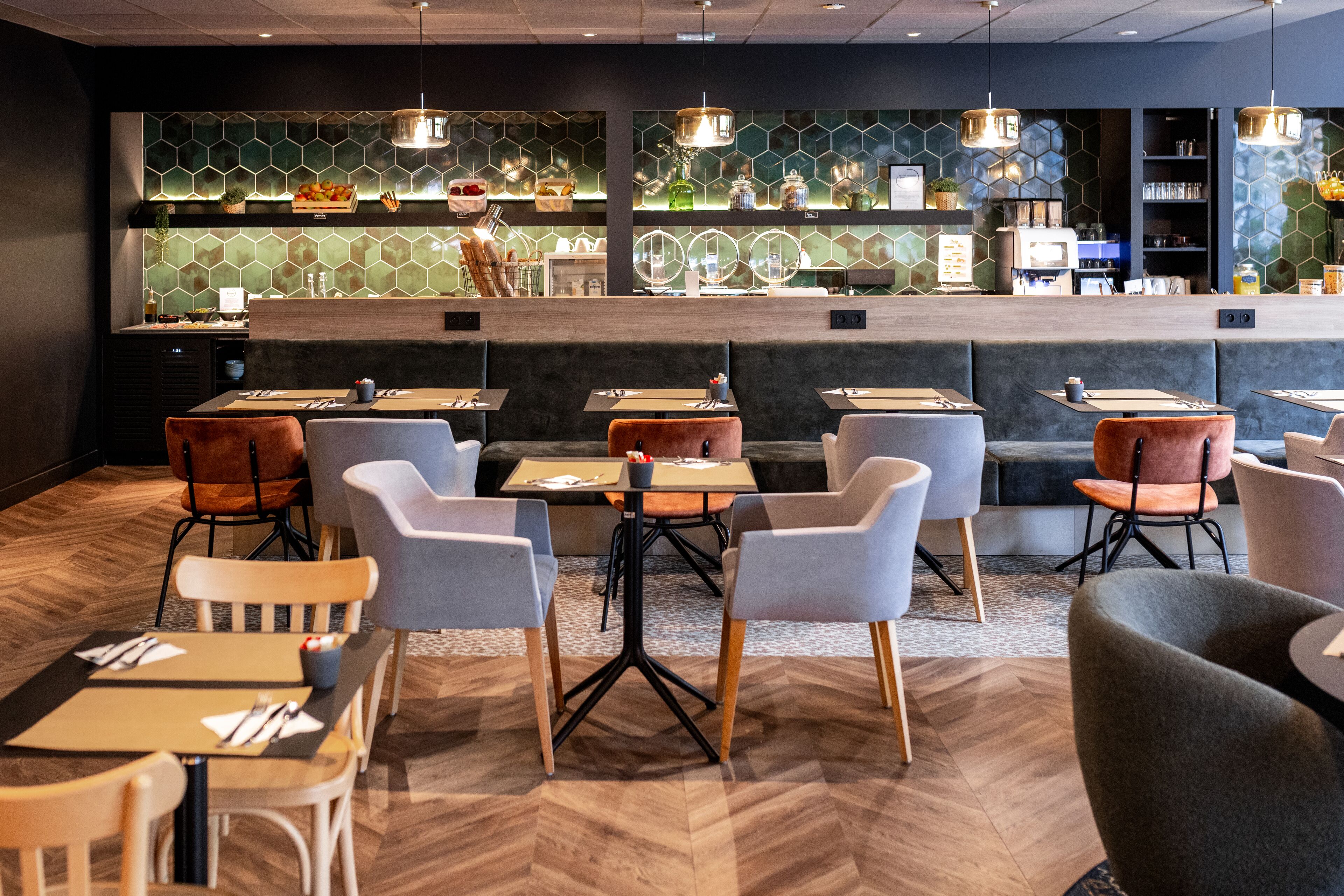 A modern restaurant interior with a bar area, seating arrangements, and a herringbone wood floor.