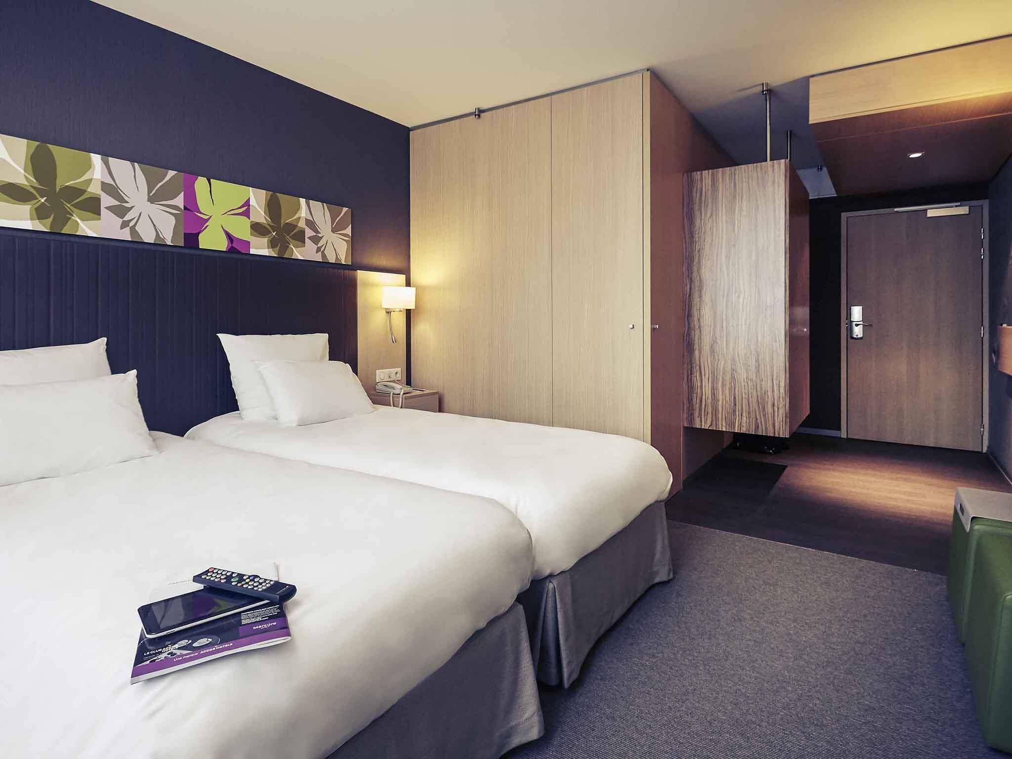Ein Hotelzimmer mit zwei Betten, einem Schreibtisch, einem Stuhl, einer Lampe und einem Kleiderschrank.