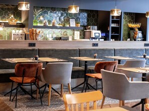 Un restaurant avec des banquettes et des tables, un comptoir et un mur recouvert de carreaux hexagonaux.