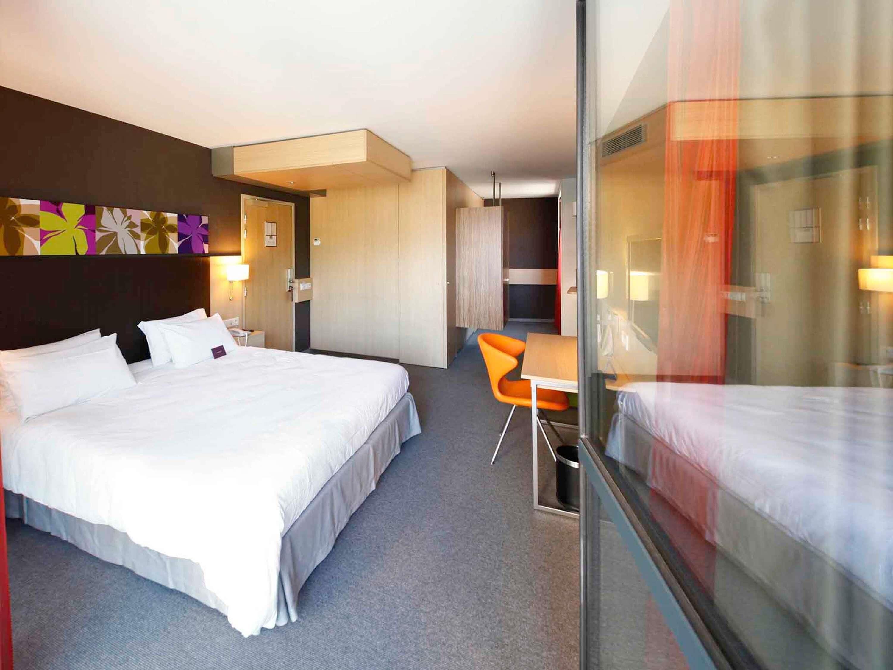 Une chambre d’hôtel avec un grand lit, une petite table et une chaise.