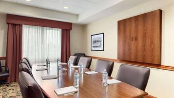 A conference room with a long table, leather chairs, water bottles, and a large wooden cabinet.