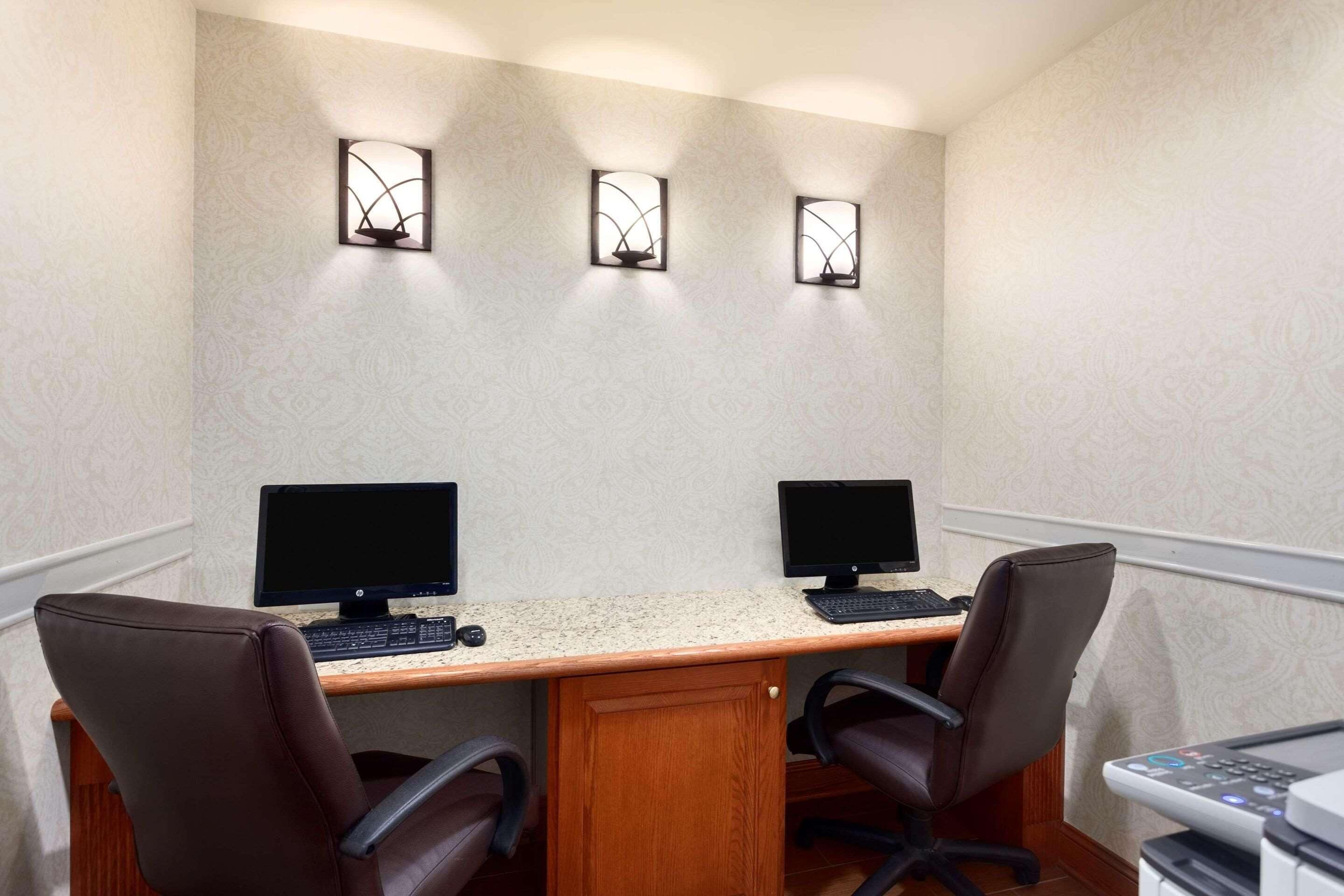 A conference room with two desks, each with a computer monitor, keyboard, and chair.