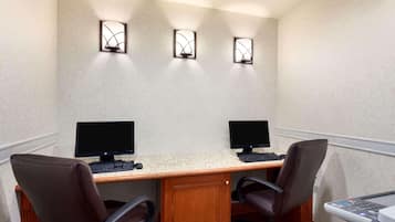A conference room with two desks, each with a computer monitor, keyboard, and chair.