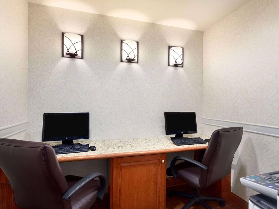 A conference room with two desks, each with a computer monitor, keyboard, and chair.