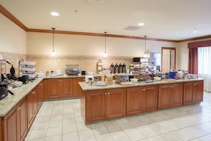A spacious kitchen with granite countertops, wooden cabinets, and various appliances including a coffee maker, toaster, and blender.