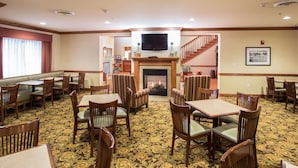 A hotel lobby with a fireplace, seating areas, and a staircase. - Country Inn & Suites by Radisson, Buffalo South I-90, NY (Buffalo)