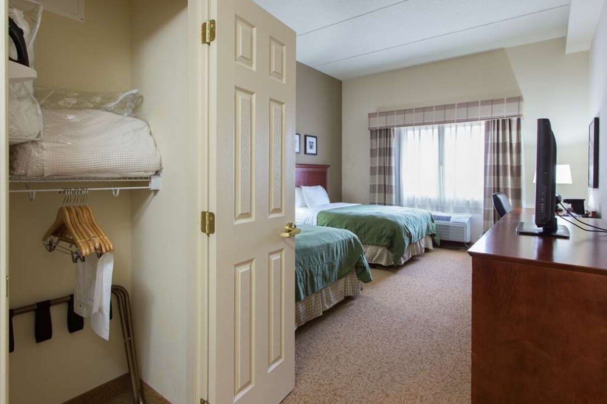 A hotel room with two beds, a desk, a television, and a wardrobe.