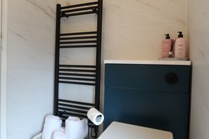 A bathroom with a towel rack, a toilet, and toiletries on a shelf. - Abbey House Bed and Breakfast (Penrith)