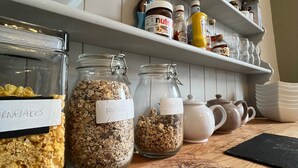 A kitchen counter with labeled jars of granola, a coffee maker, and a variety of kitchen items on shelves. - Abbey House Bed and Breakfast (Penrith)