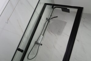 A glass-enclosed shower with a handheld showerhead and a fixed overhead rainhead. - Abbey House Bed and Breakfast (Penrith)
