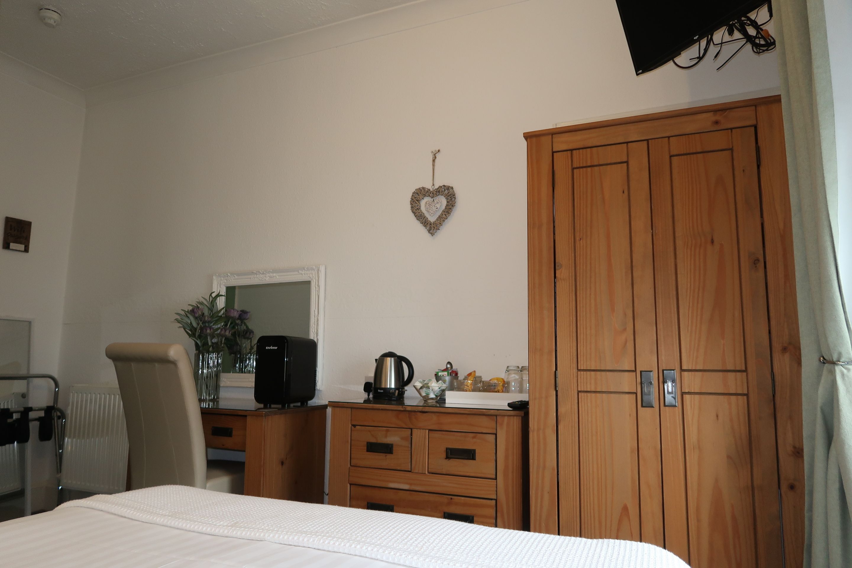 Une chambre à coucher comprenant un lit, une commode, un miroir, une bouilloire et une armoire.