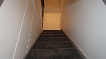 Uma escadaria com degraus revestidos a carpete, subindo.