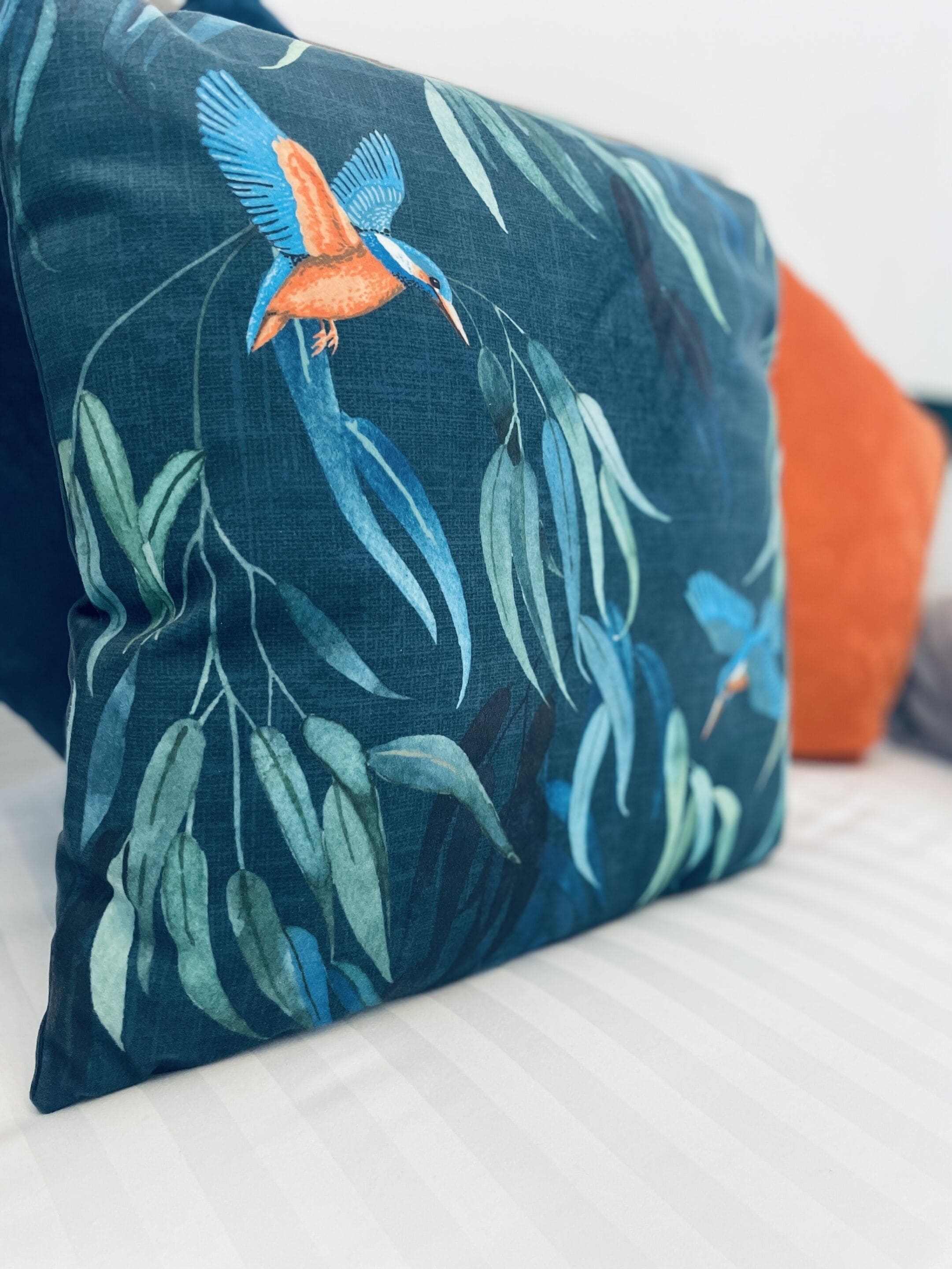 A pillow with a bird and leaves design.