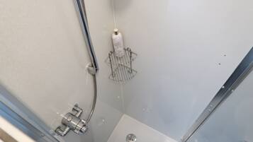 A shower with a handheld showerhead, a handheld soap dispenser, and a metal shower tray.
