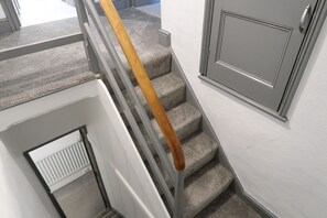 A staircase with a wooden handrail and grey carpeted steps. - Abbey House Bed and Breakfast (Penrith)