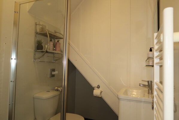Un baño con inodoro, lavamanos y cabina de ducha de vidrio.