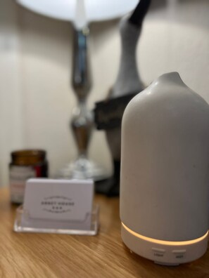 Ein Nachttisch mit einer weißen Lampe, einem kleinen weißen Gerät und einer Namenskarte.