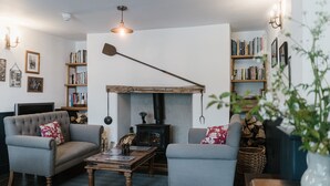 A cozy living room with two armchairs, a coffee table, a fireplace, and bookshelves. - Bridge House (Tiverton)