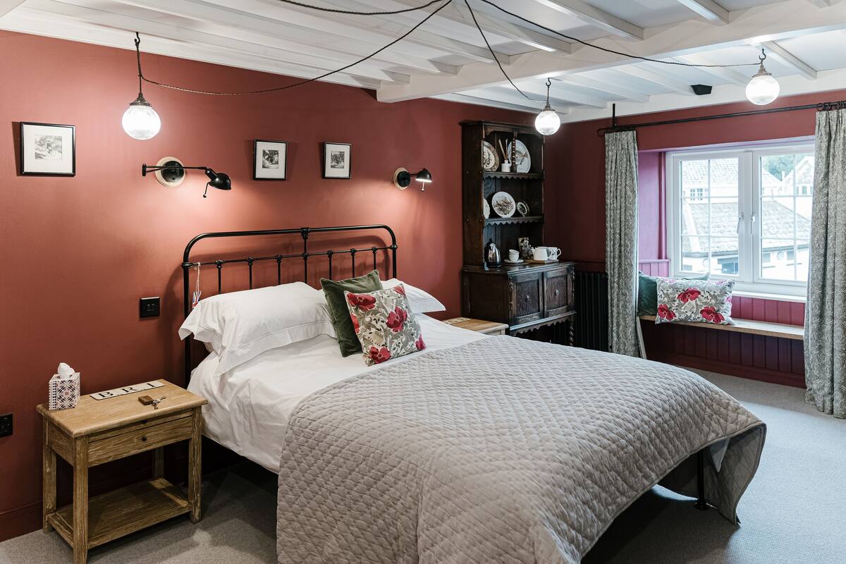 A neatly arranged bedroom with a bed, bedside table, and a window with curtains.