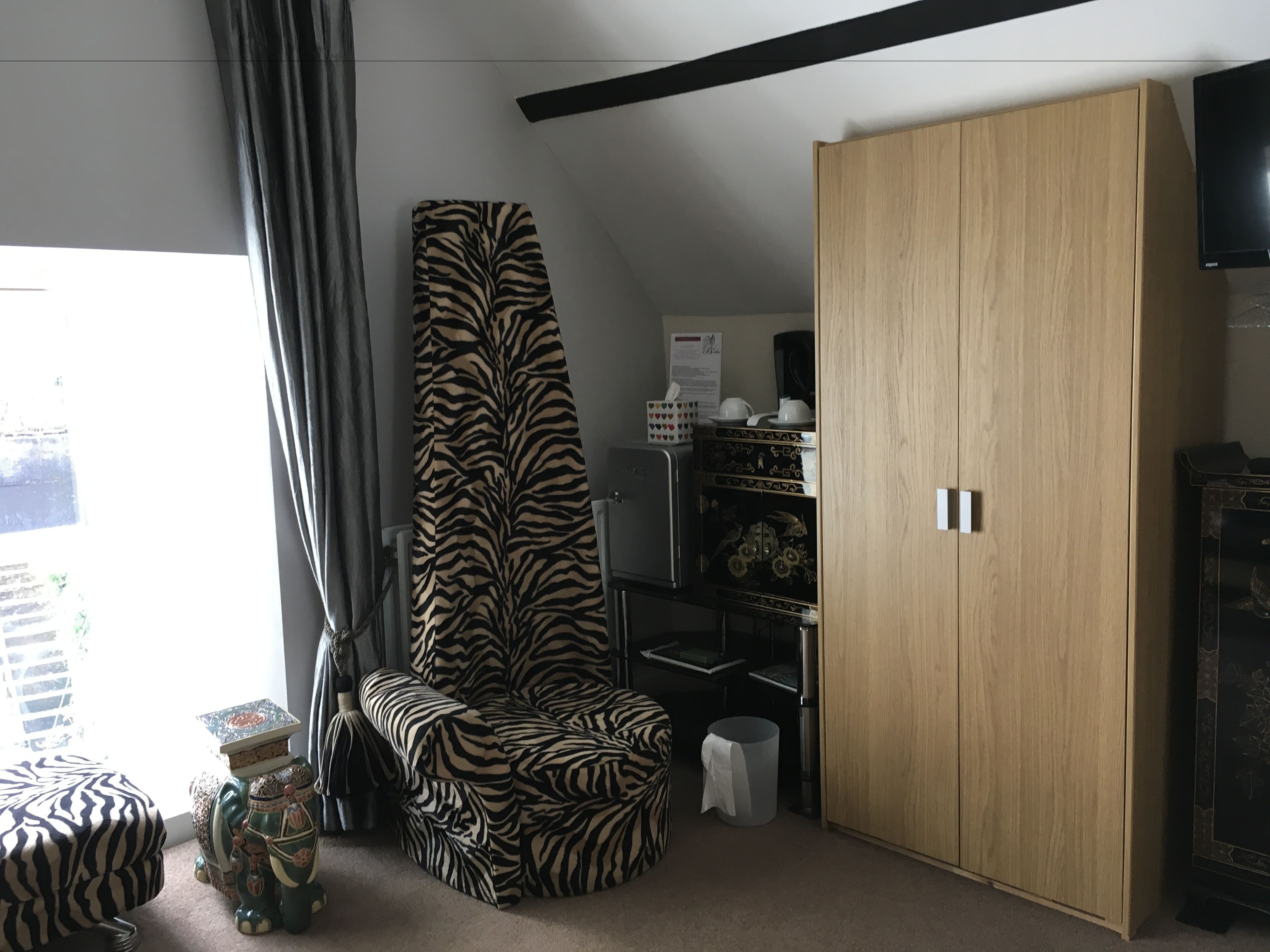 Un salón moderno con un sillón estampado de cebra, un armario de madera y una mesa de centro con adornos.