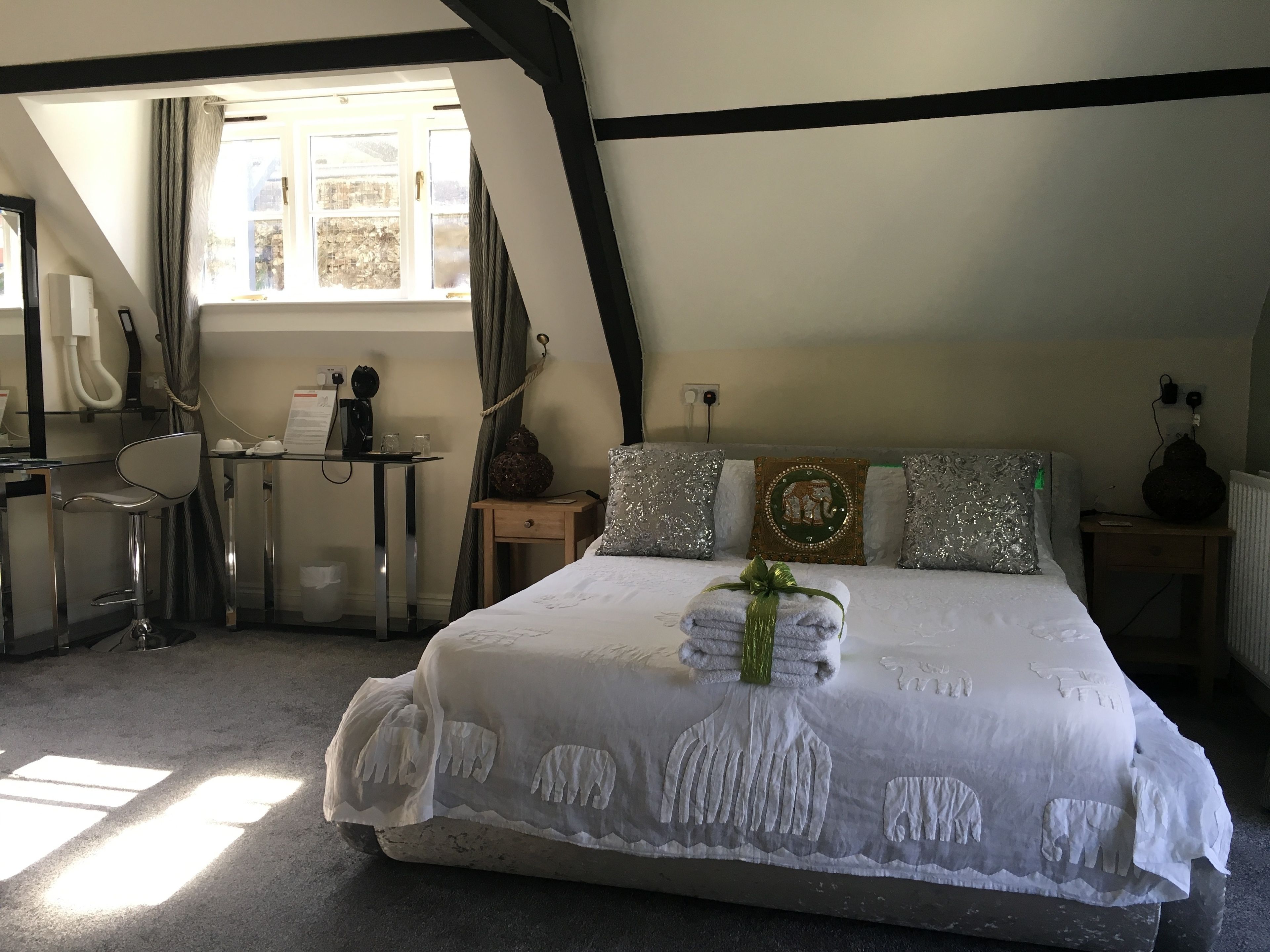 Un dormitorio con cama, escritorio, silla y ventana.