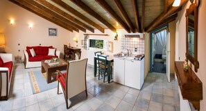 Un espacio habitable compacto con comedor, kitchenette y un sofá rojo.