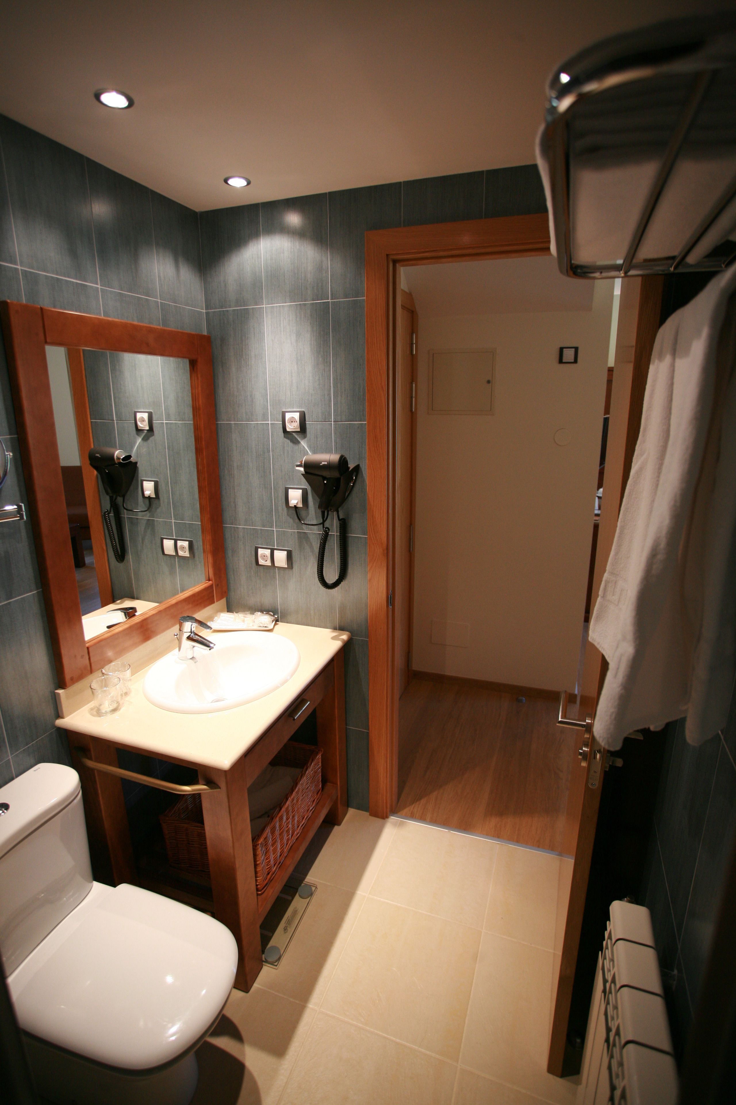Ein Badezimmer mit einer weißen Toilette, einem Waschbecken mit Spiegel darüber und einem Föhn an der Wand.
