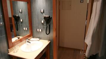 Ein Badezimmer mit einer weißen Toilette, einem Waschbecken mit Spiegel darüber und einem Föhn an der Wand.