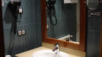 Casa de banho com lavatório, espelho, secador de cabelo e porta-toalhas.