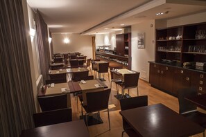 Un restaurante con varias mesas y sillas, una zona de bar y una exhibición de cristalería.