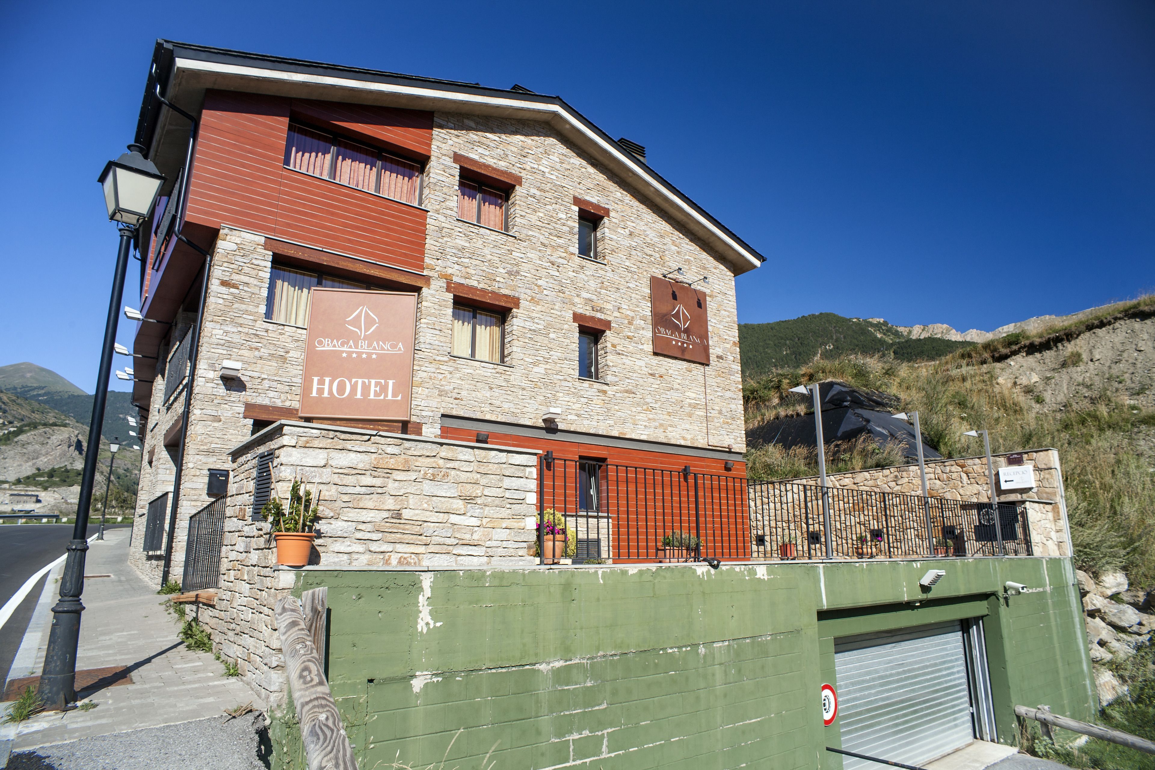A hotel with a stone facade, multiple windows, and a green gate.