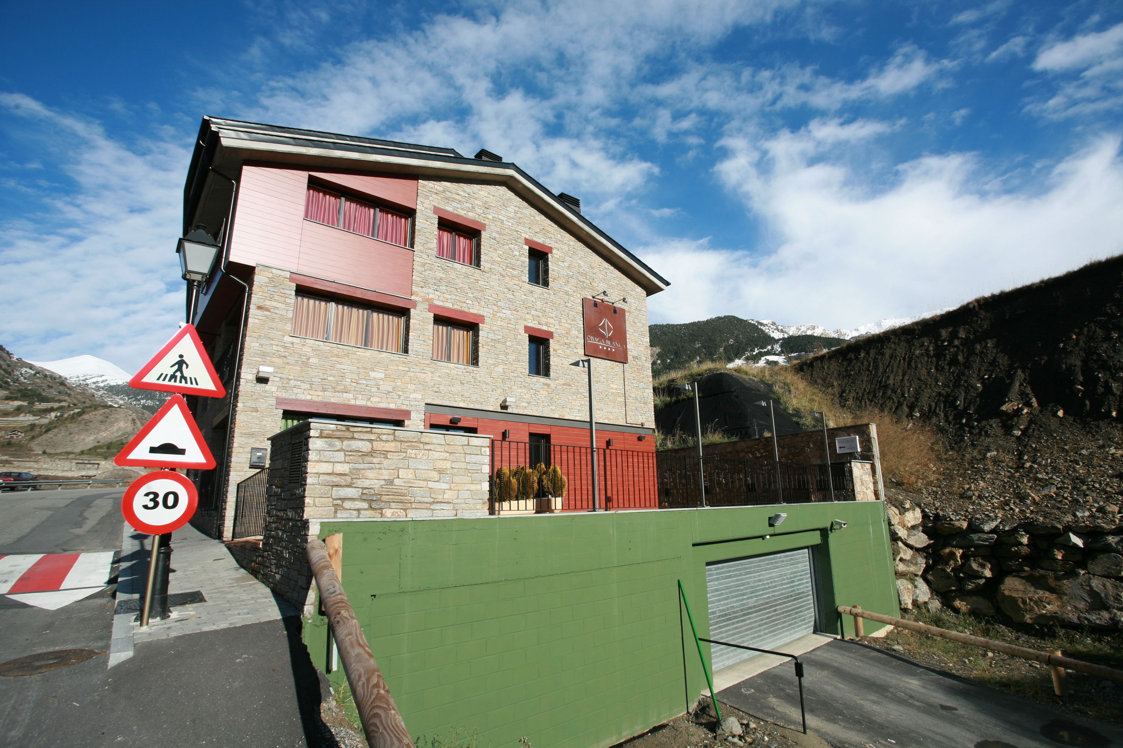 Un immeuble à plusieurs étages, doté d’une façade en pierre, de touches de couleur rouge et d’une enseigne indiquant la présence d’une station de ski.