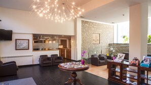 A modern lobby with a round wooden table displaying magazines, a stone wall, and a staircase. - Hotel Obaga Blanca (Canillo)