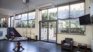 A spacious living area with a staircase, a dining table with a placemat, a comfortable chair, and a television mounted on the wall. - Hotel Obaga Blanca (Canillo)