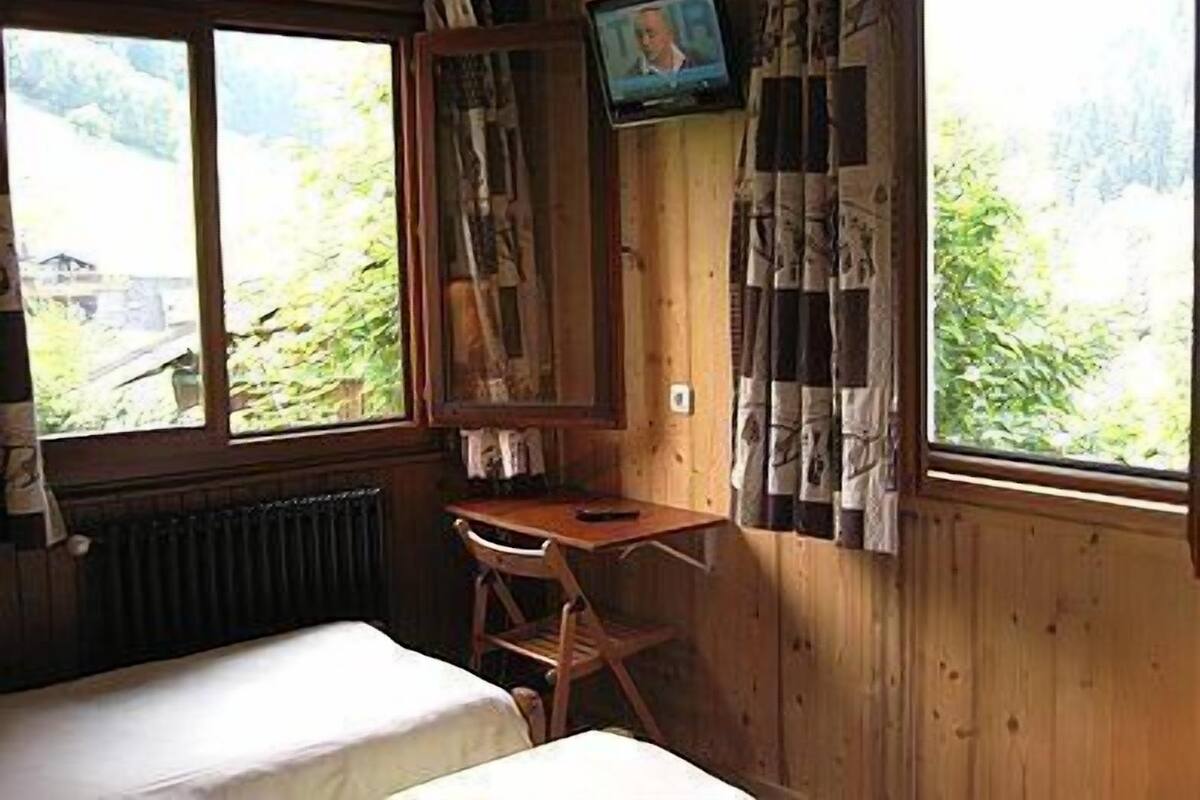 Een houten kamer met een bed, een bureau en een televisie.