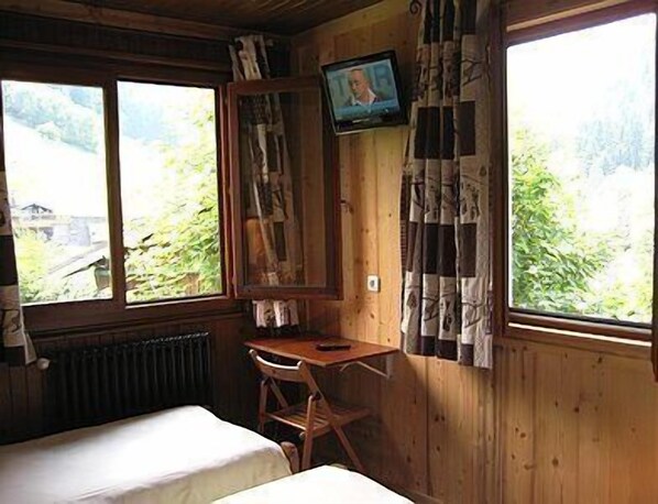 Una habitación tipo cabaña de madera con una cama, un escritorio y un televisor.