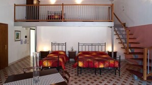 Una habitación con dos camas, una mesa y una escalera.