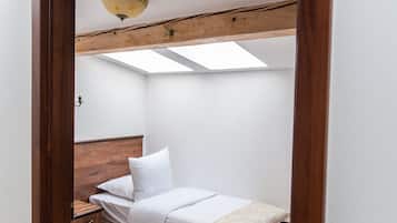 Una habitación con dos camas, vigas de madera, un tragaluz y un marco de puerta de madera.
