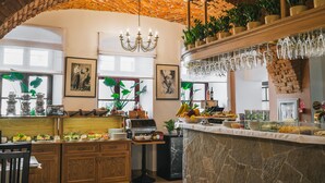A kitchen with a stone arch, wooden cabinets, a coffee machine, and a buffet with various food items.