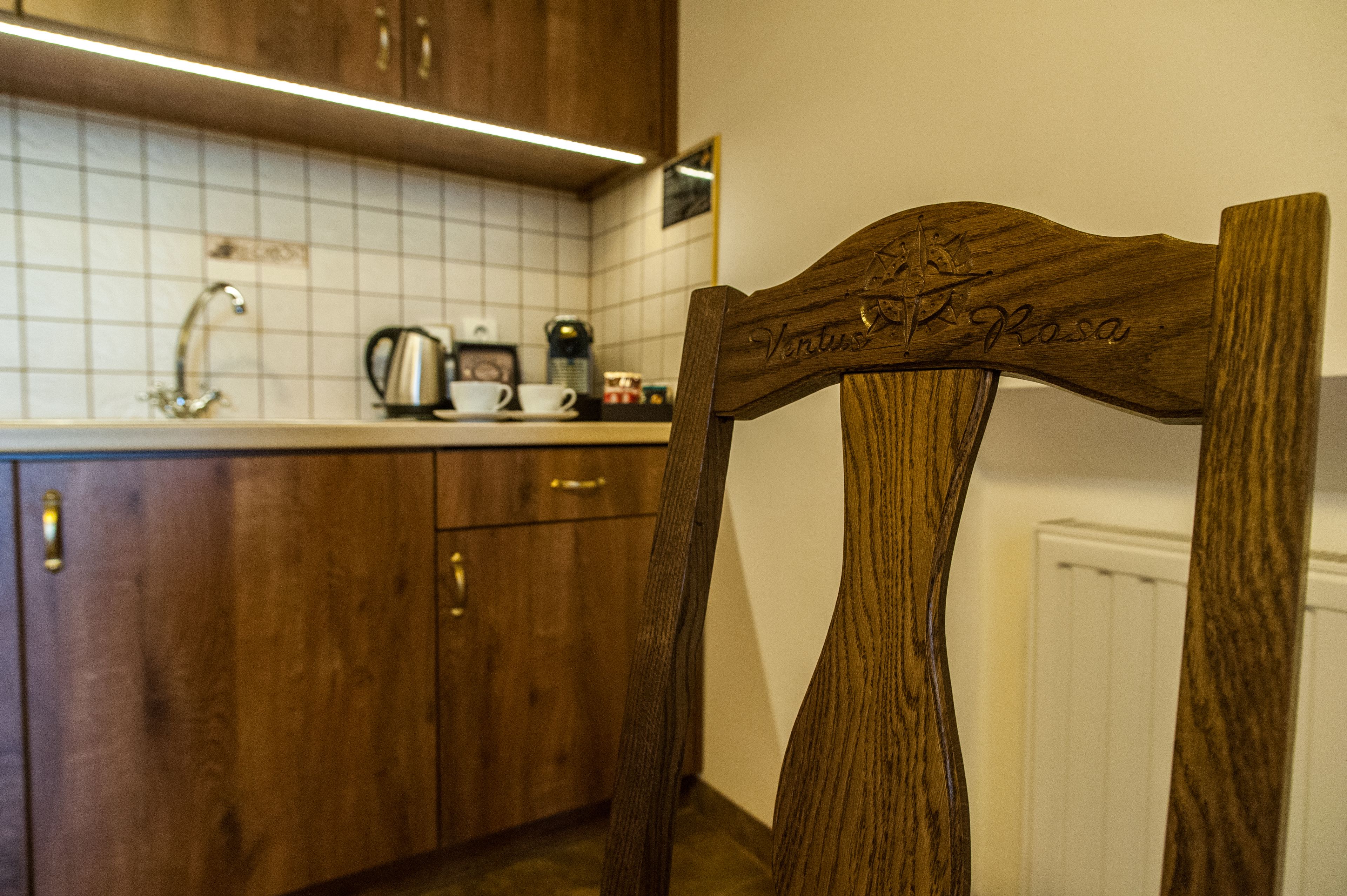 A wooden chair with "Ventus Rosa" engraved on the backrest in a kitchen setting.