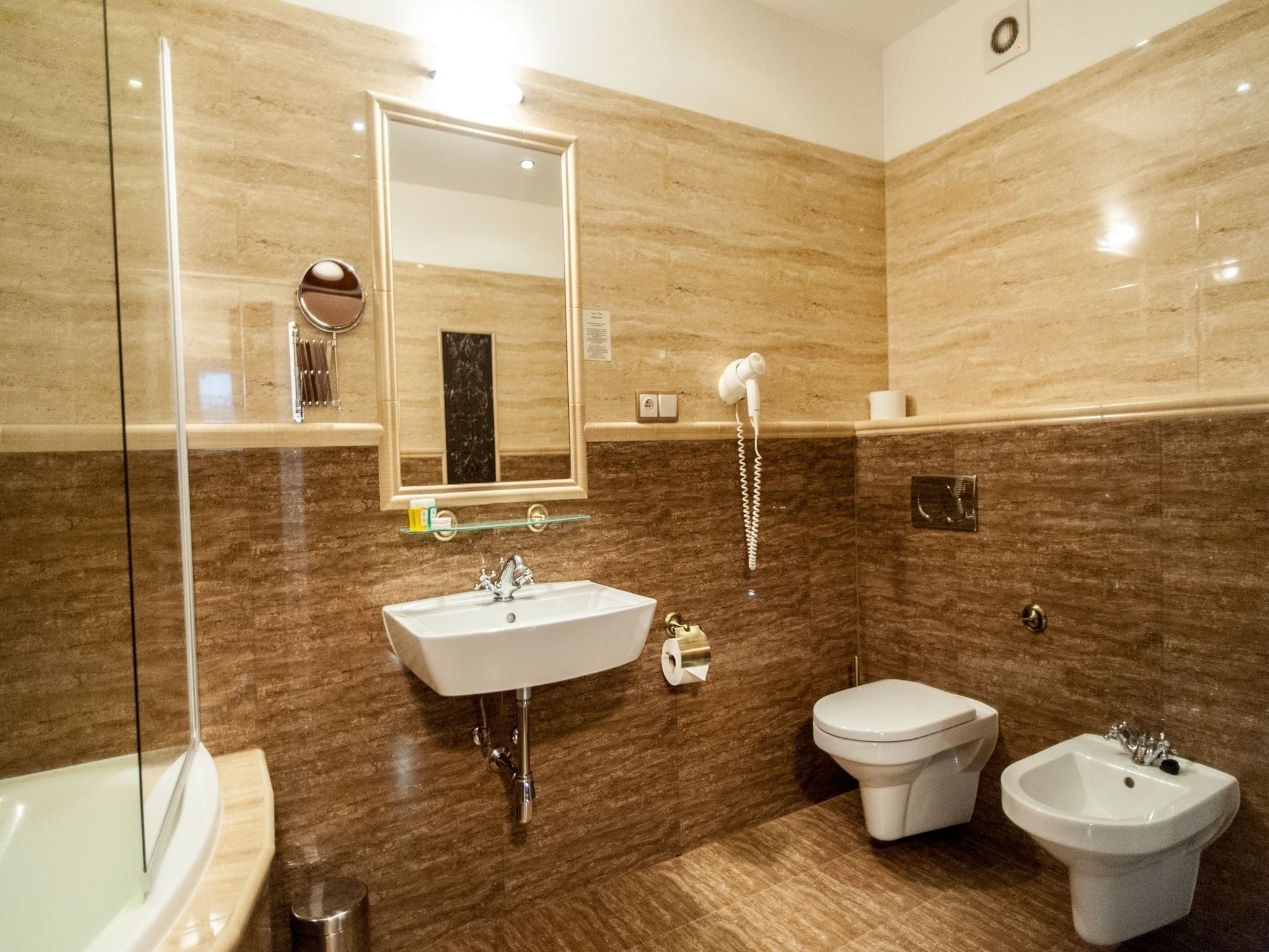 Un baño moderno con un espejo grande, un lavamanos, un bidé y una bañera.