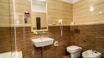 Un baño moderno con un espejo grande, un lavamanos, un bidé y una bañera.