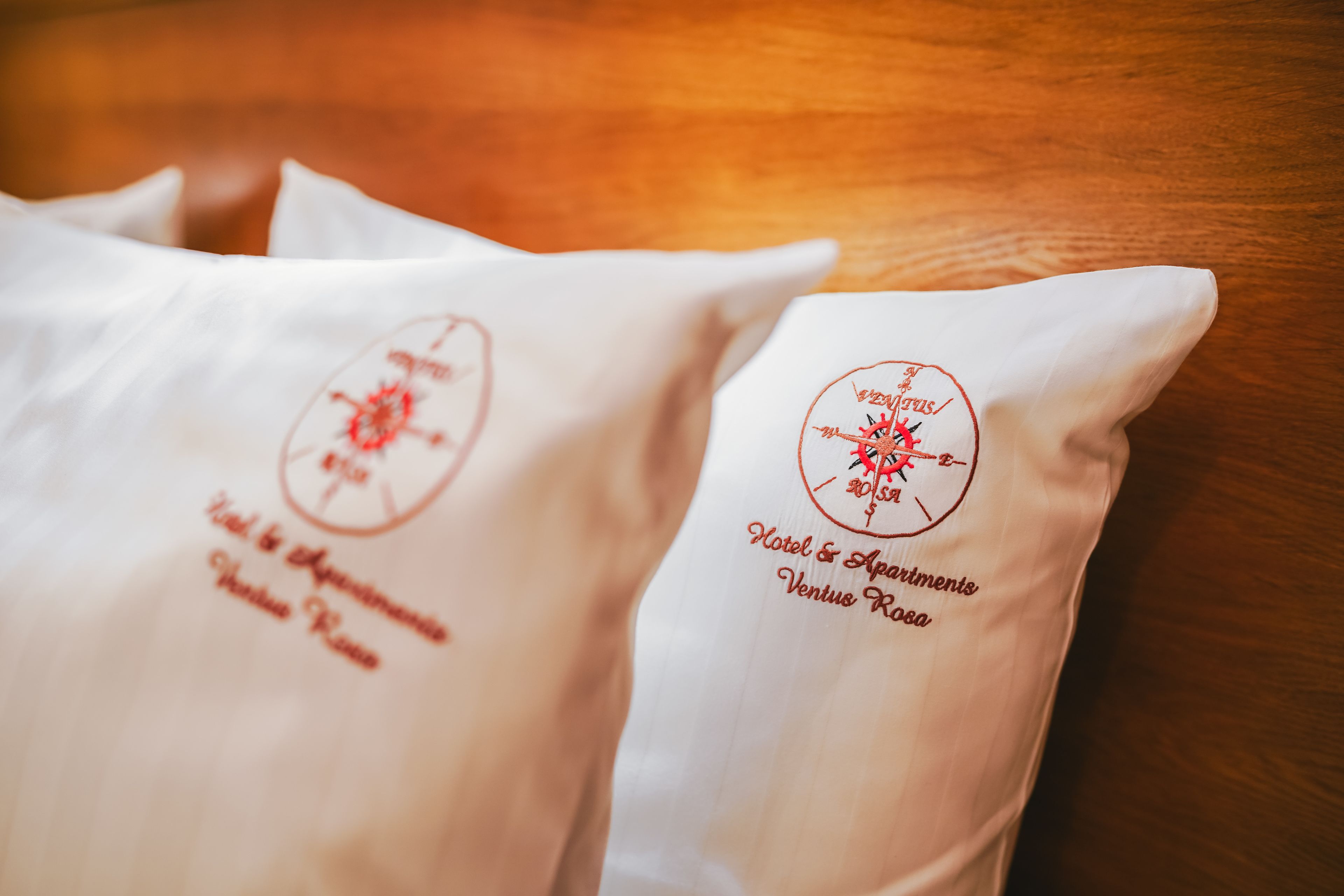 Two pillows with embroidered text indicating a hotel and apartments in Venice, Rome.